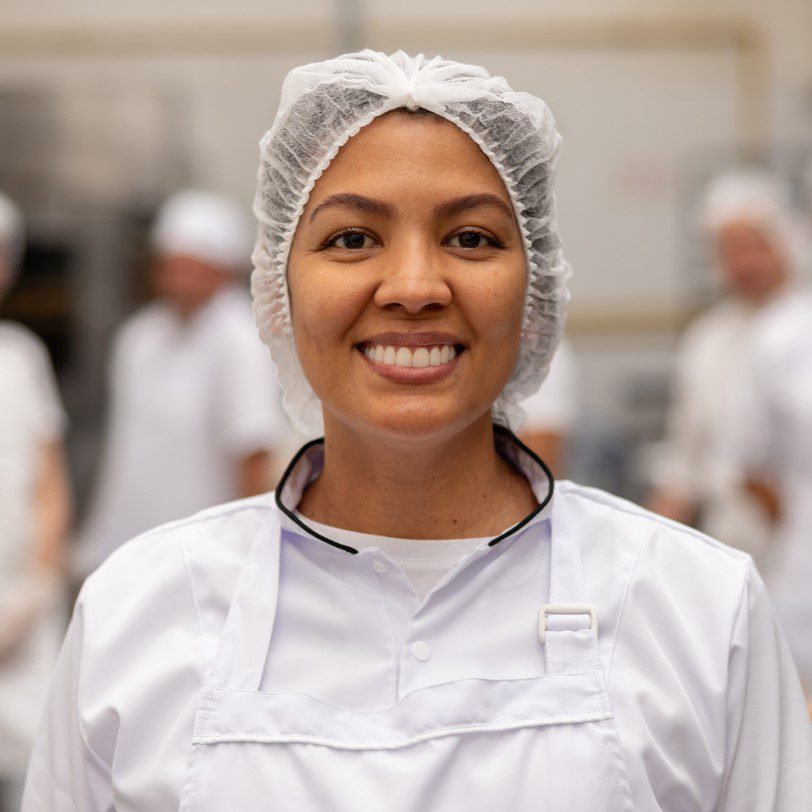 Woman wearing hair net and apron smiling at camera